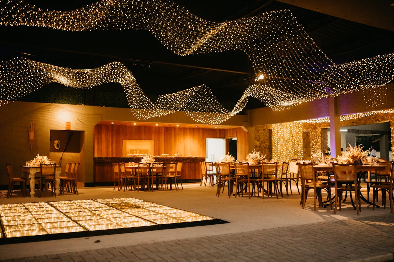 Chic restaurant interior featuring wooden tables, chairs, and warm string lights.
